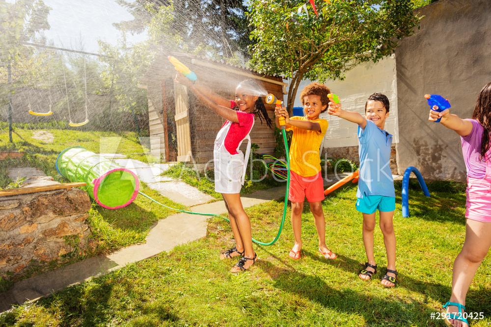 enfants qui font une bataille d'eau avec des pistolets à eau dans le jardin 
